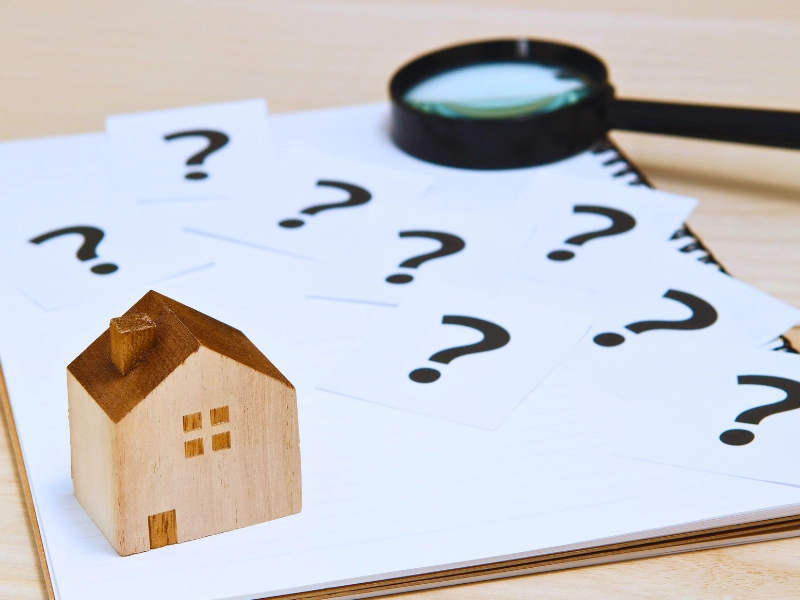 Blog 2 Wooden house model, question mark notes, and magnifying glass.